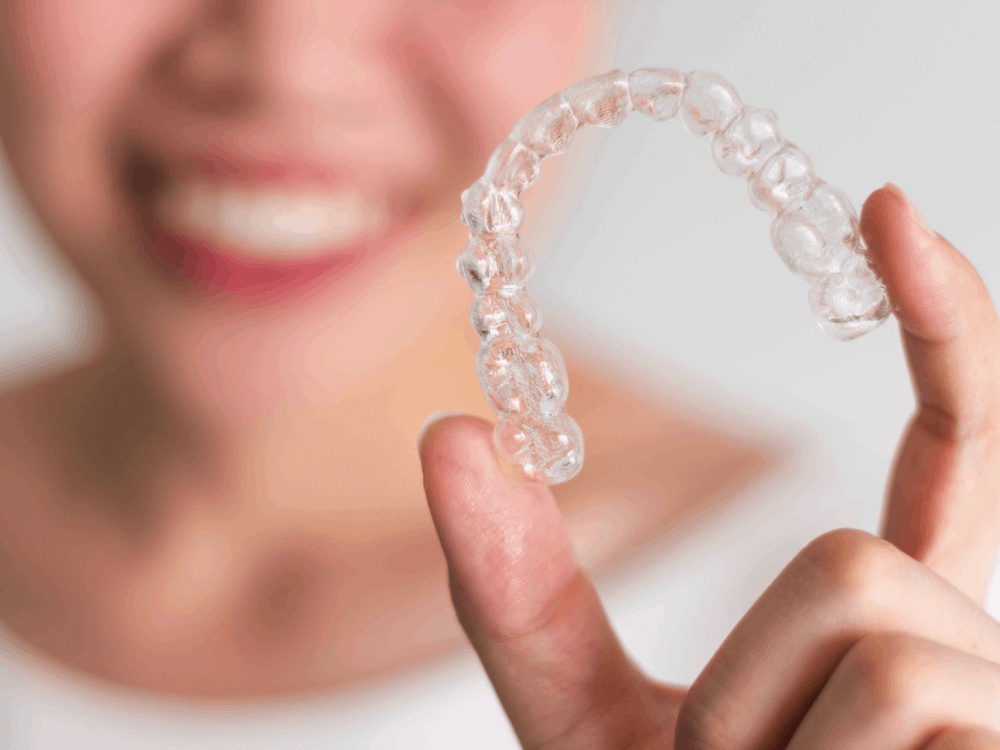 a woman holding up clear aligner