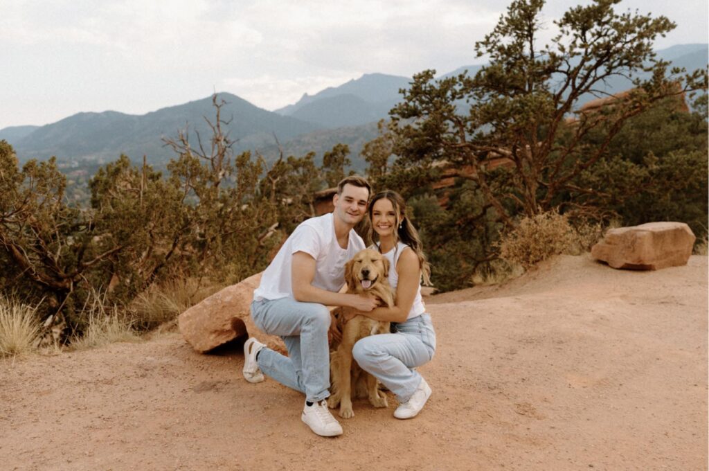Doctor Dore, Julia and their golden retriever smiling side by side in a warmly lit setting, dressed in casual, coordinated outfits.